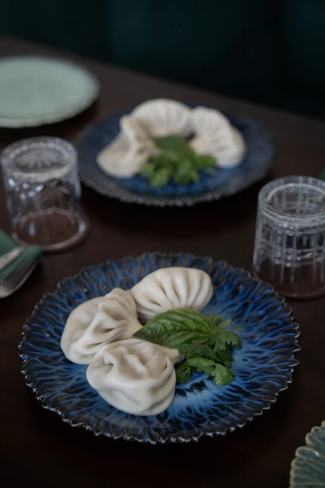 Khinkali con hierbas frescas en un plato azul en Tarragon, Uluwatu
